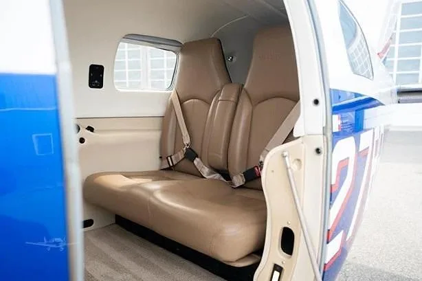 The tan leather passenger seats in the cabin of a small aircraft, viewed from the open door.